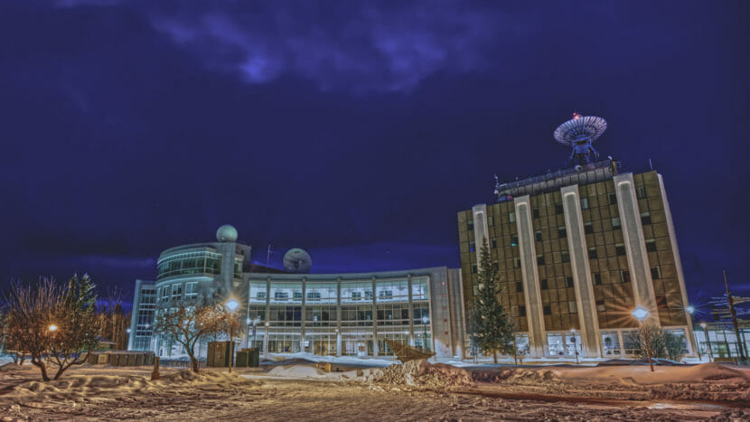 Two research buildings on a hill. The one on the right is older and has a large satellite dish on its roof, pointed up.