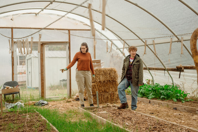 Two women standing inside a greenhouse.