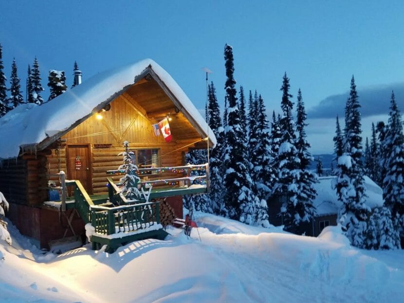 A log cabin in the snow at night.