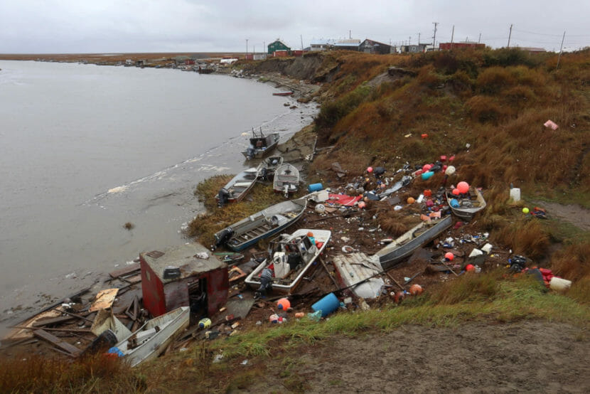 Boats and fishing gear jumbled together along the shore outside a village.