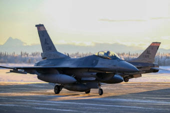 Two F-16s taxiing on a runway.
