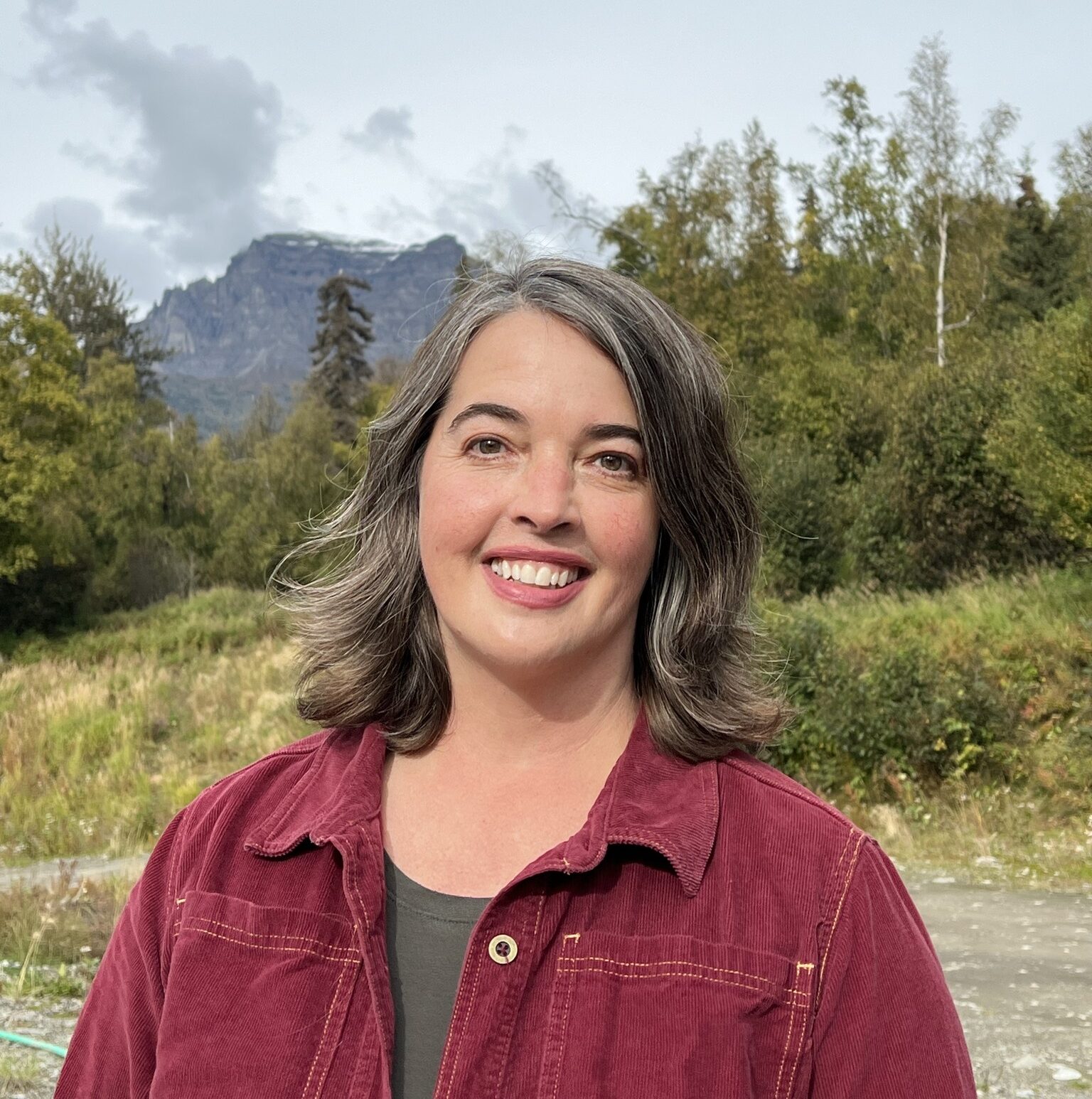Author Eowyn Ivey photographed in front of woods and mountains. 