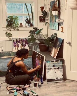 Painter Jennifer gross seated on the floor working on a painting.