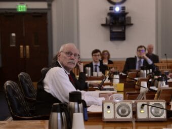 A man listens while sitting before a committee