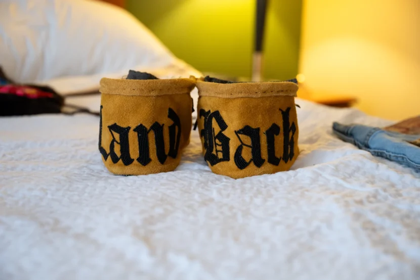 a pair of moccasins that say "land back" on them
