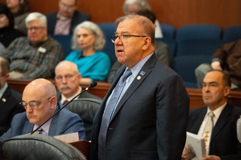 Man speaking in crowded legislative chamber