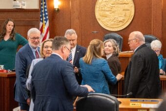 Senators and representatives speak with one another on the floor of the Alaska House of Representatives during a joint session on May 14, 2025.