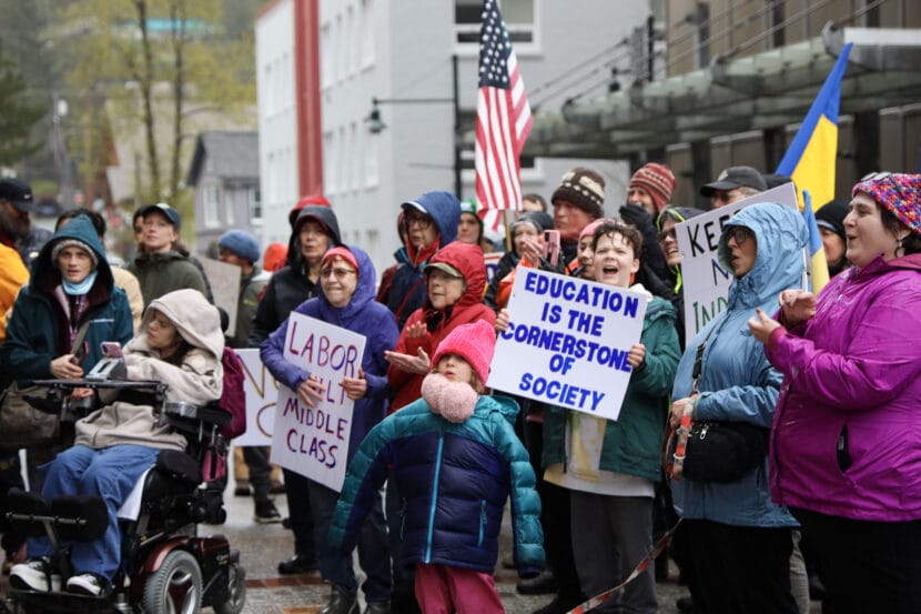 A group of protesters hold signs and American flags outside the Alaska State Capitol in downtown Juneau, 