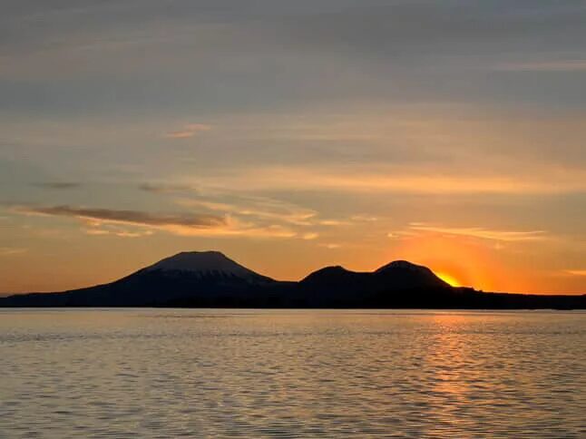 the sun sets behind mountains overlooking the ocean of Sitka Sound