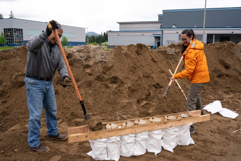 Benjamin Coronell and S'eiltin Jamiann Hasselquist with the Juneau Tlingit and Haida Community Council fill sandbags in the parking lot behind Thunder Mountain Middle School. (Photo by Alix Soliman/KTOO
