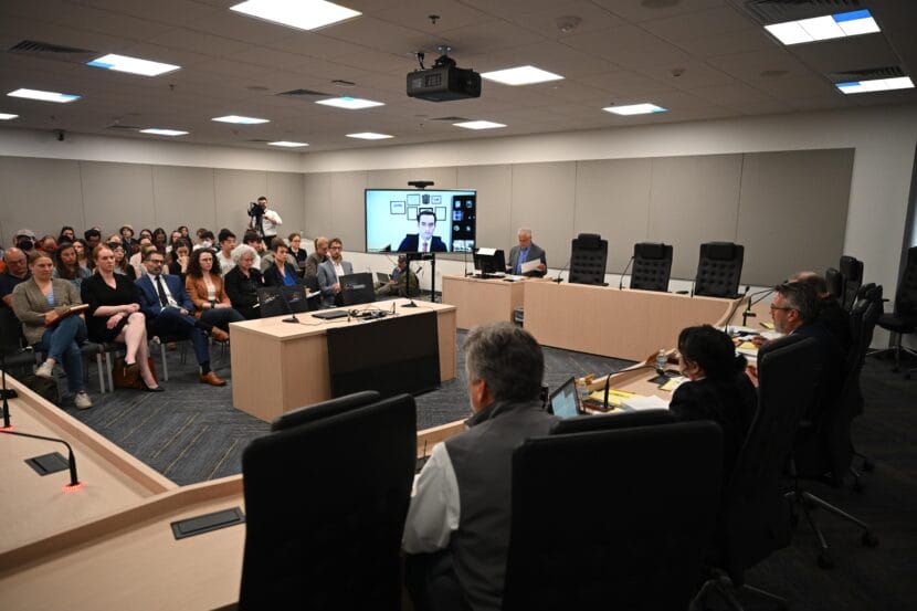 A hearing room. Public section is full.