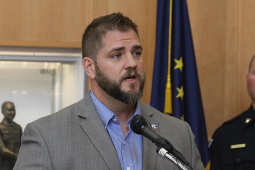 man with brown hair and beard speaks into microphone