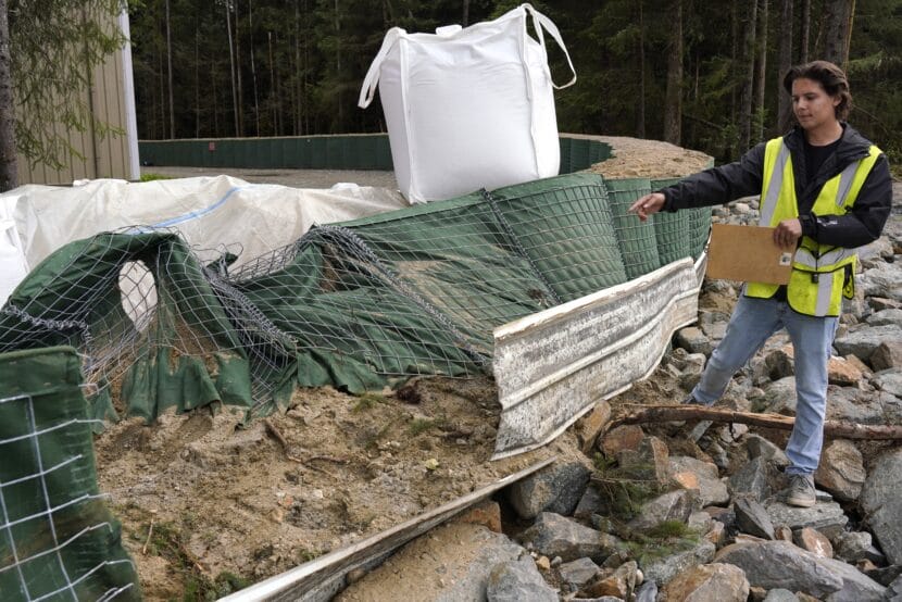 Nick Druyvestein points to the HESCO blocks that were crushed by a tree near Dimond Park Field house during the August 13 flood. (Photo by Alix Soliman/KTOO)