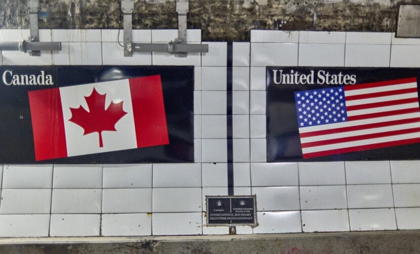 A vertical black line on the inner wall of the Detroit-Windsor Tunnel marks the border between Canada and the United States. On the left side of the line is a Canadian flag, and on the right side of the line is an American flag.