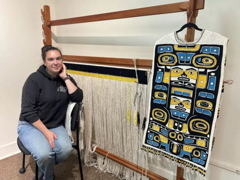 Lingít weaver Tleinax Shaawat Sydney Akagi poses with two of her creations displayed at the Sheldon Jackson Museum.