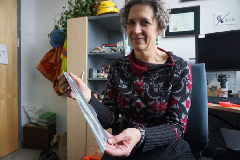 A woman sitting in an office holds a piece of slate