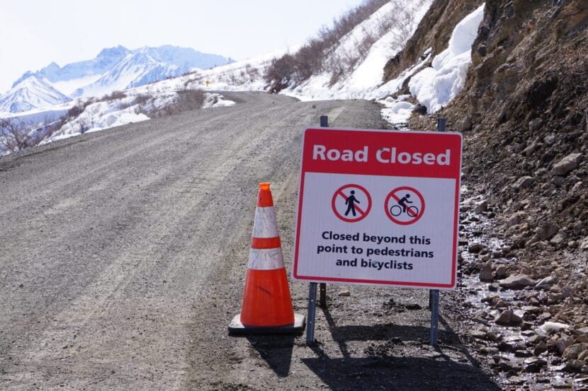 A sign along a snowy hillside road warns of landslide risk