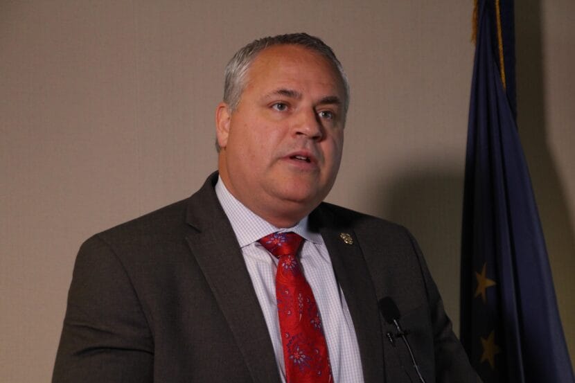 a man with gray hair and a red tie speaks