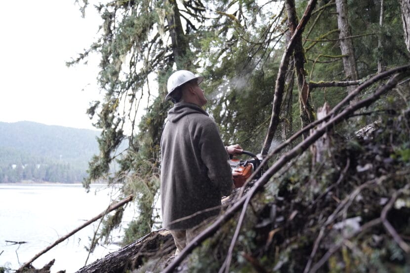 Mark Krumwiede saws through a branch along the edge a landslide that washed out Auke Lake Trail in September 2025. (Photo by Alix Soliman/KTOO)