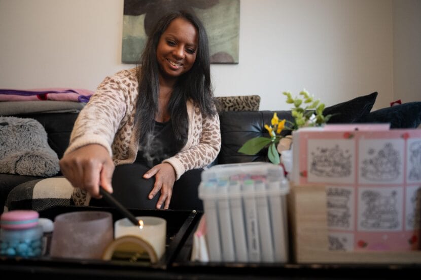 A woman in a sweater lights a candle.