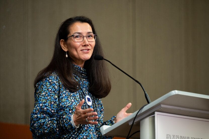 a woman talks into a microphone at a podium on stage