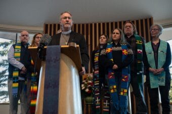 A man stands at a podium with a group behind him.