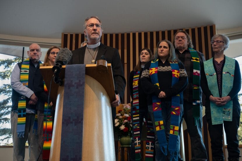 A man stands at a podium with a group behind him.