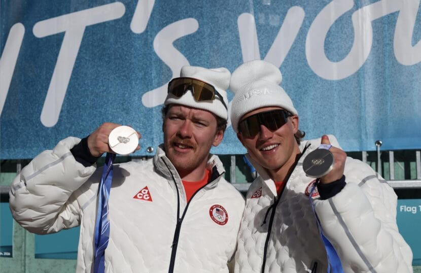 Two men holding silver medals