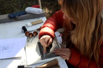 Printmaker Baylee Pearson carves a new design into linoleum during a recent arts event.